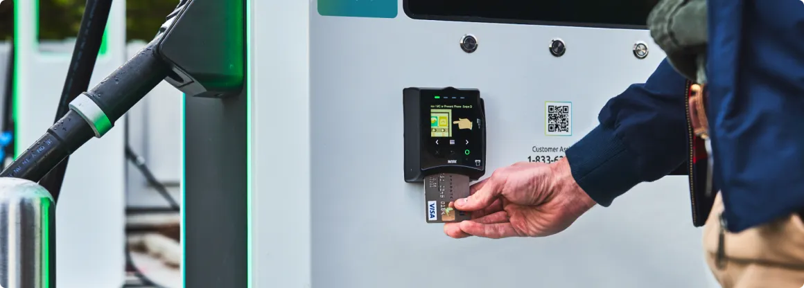 Closeup of a person putting a credit card into a card reader at an Electrify America charging station.