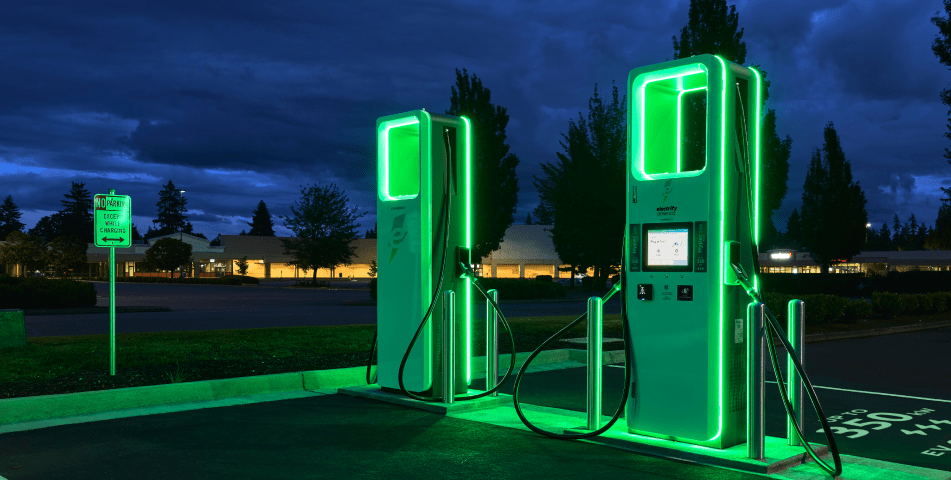 Two Electrify America charging stations glowing green at night