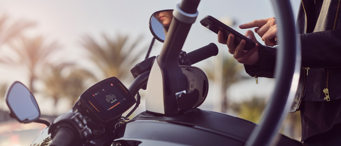 A person using a mobile phone to start a charge for their Harley Davidson Livewire motorcycle. An EA
    connector is plugged into the motorcycle.