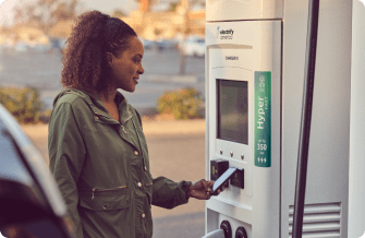 Woman using her phone to pay at an Electrify America charging station