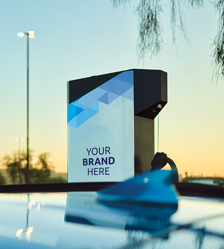 The roof of an EV with an Electrify America charging station and a sunset in the background.