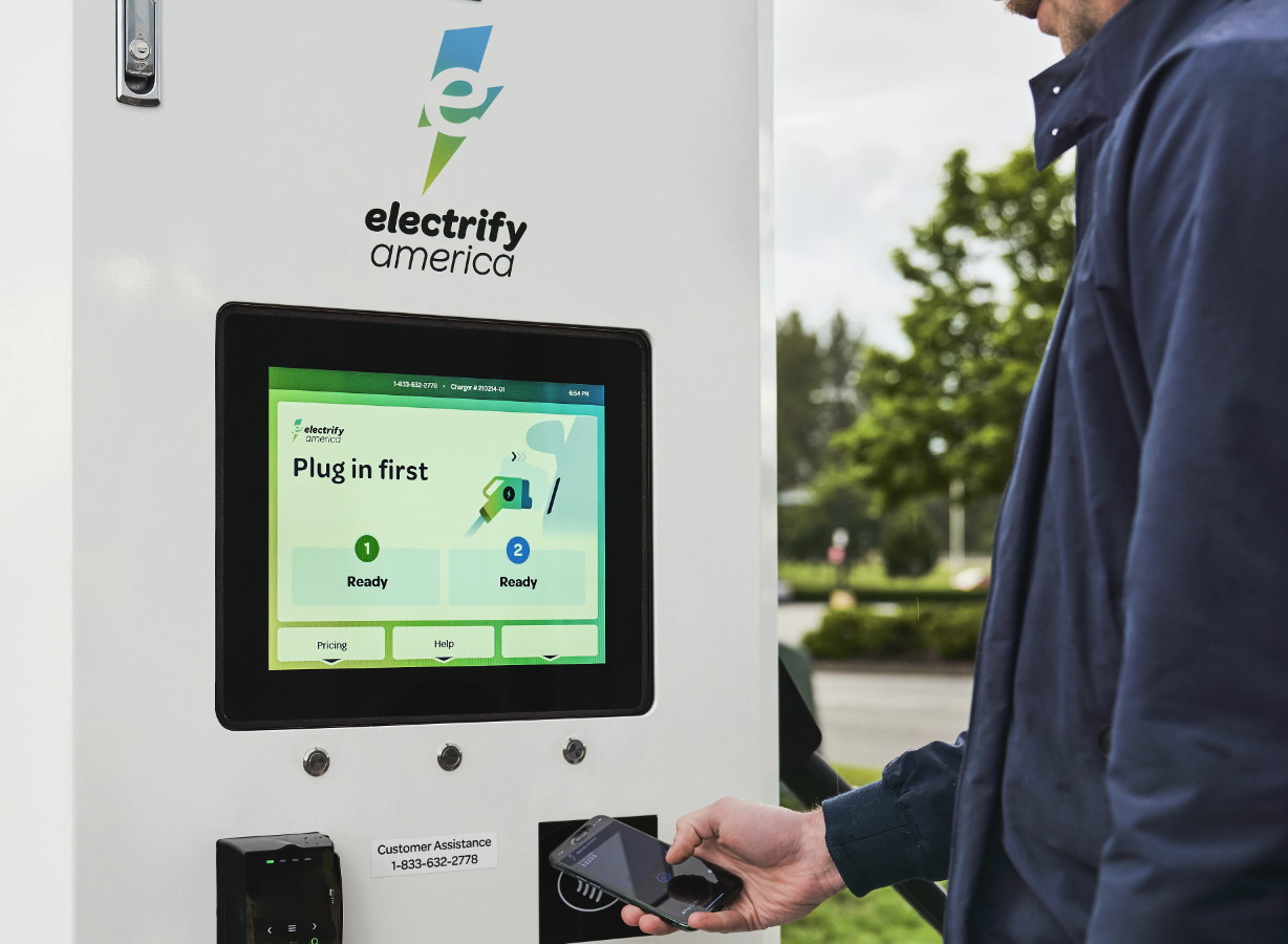 Electrify America charging station with person using their mobile phone to set up their charging session